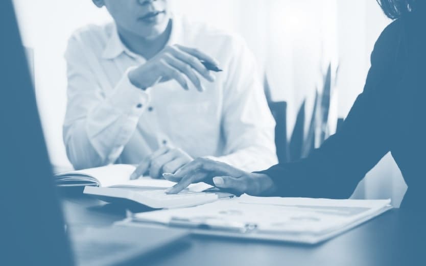 People writing on a stack of papers